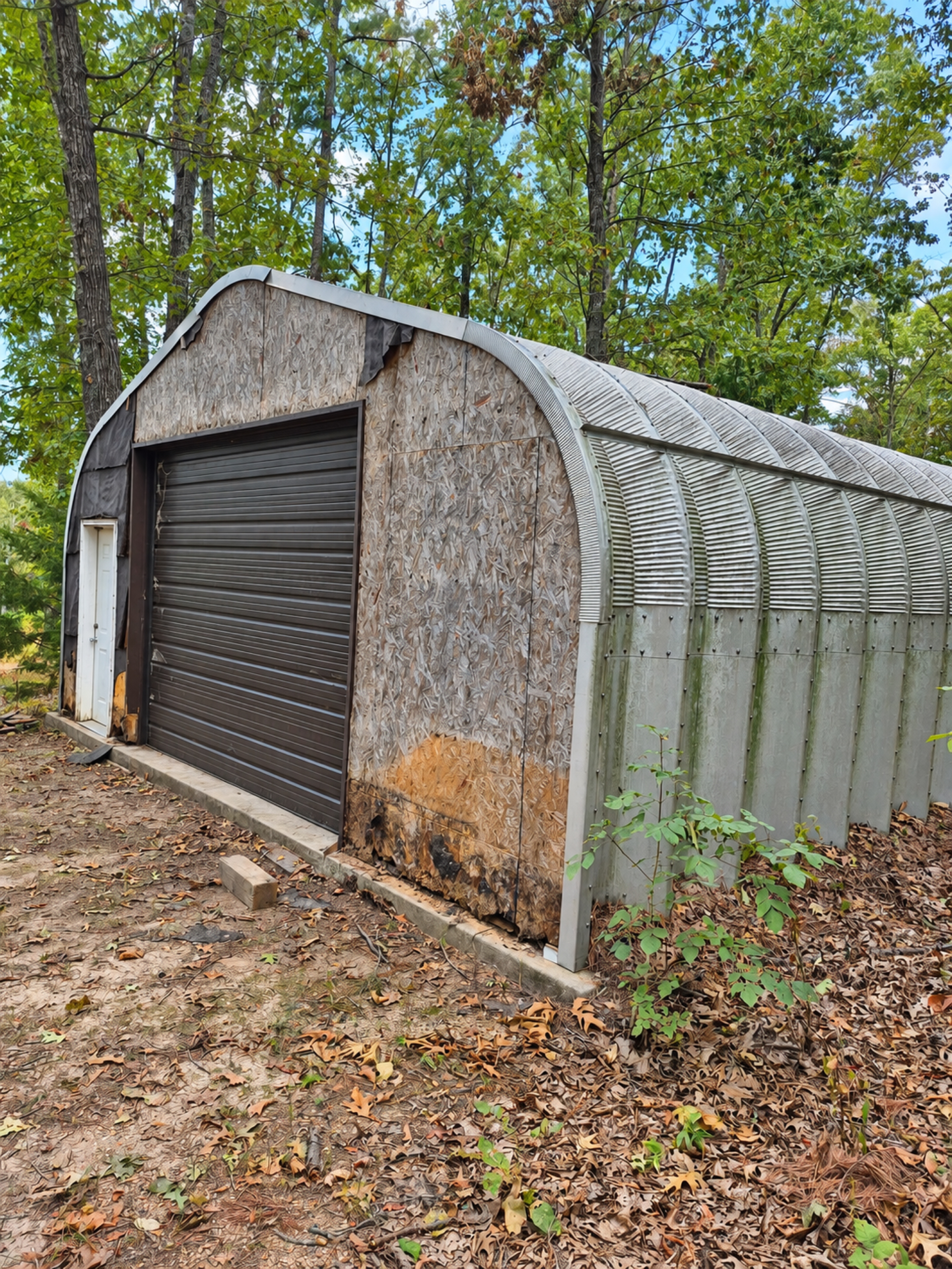 Angled view of the garage showing worn front sheathing and its curved metal side wall