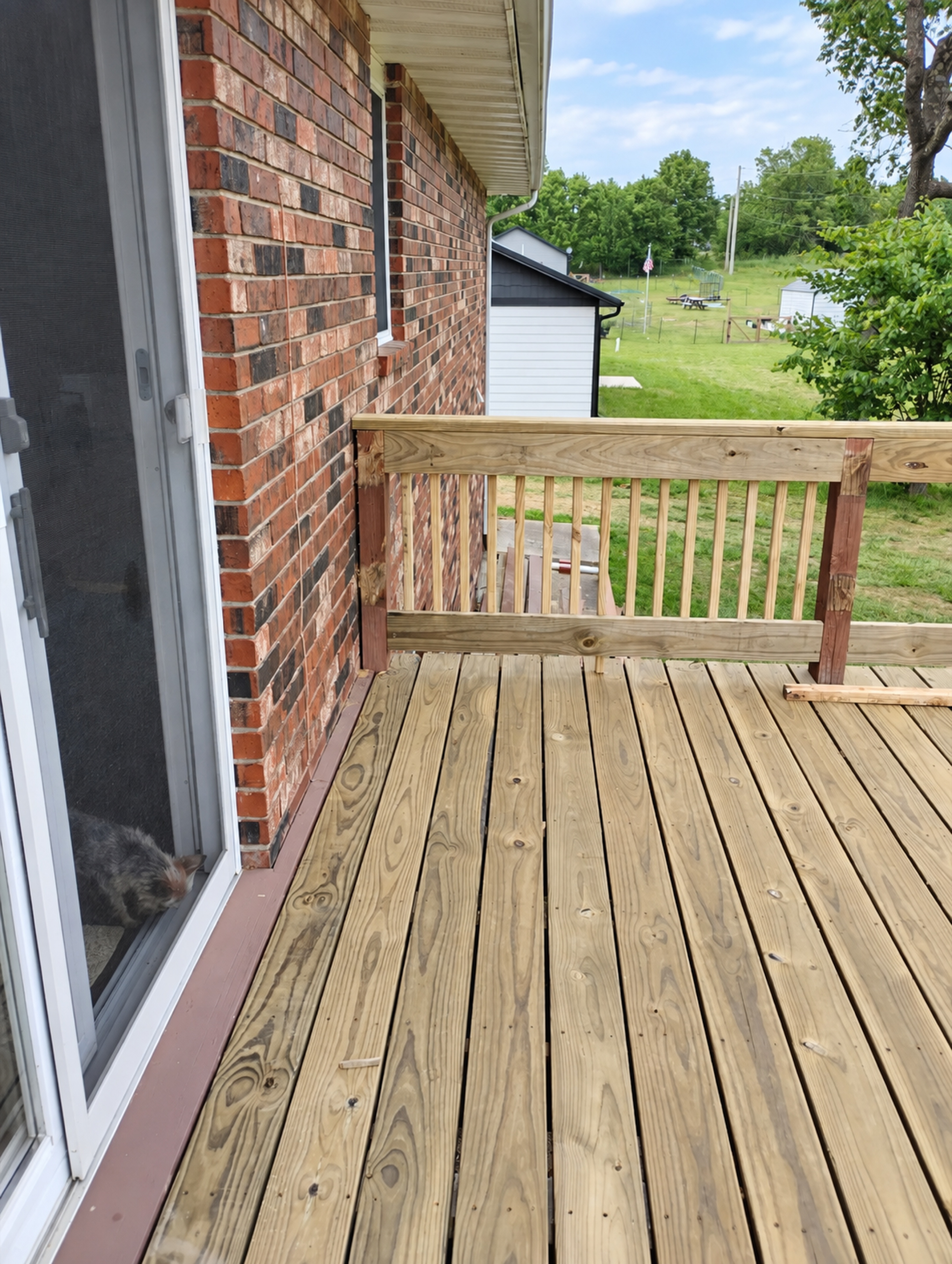 New upper deck surface and railing beside the brick exterior
